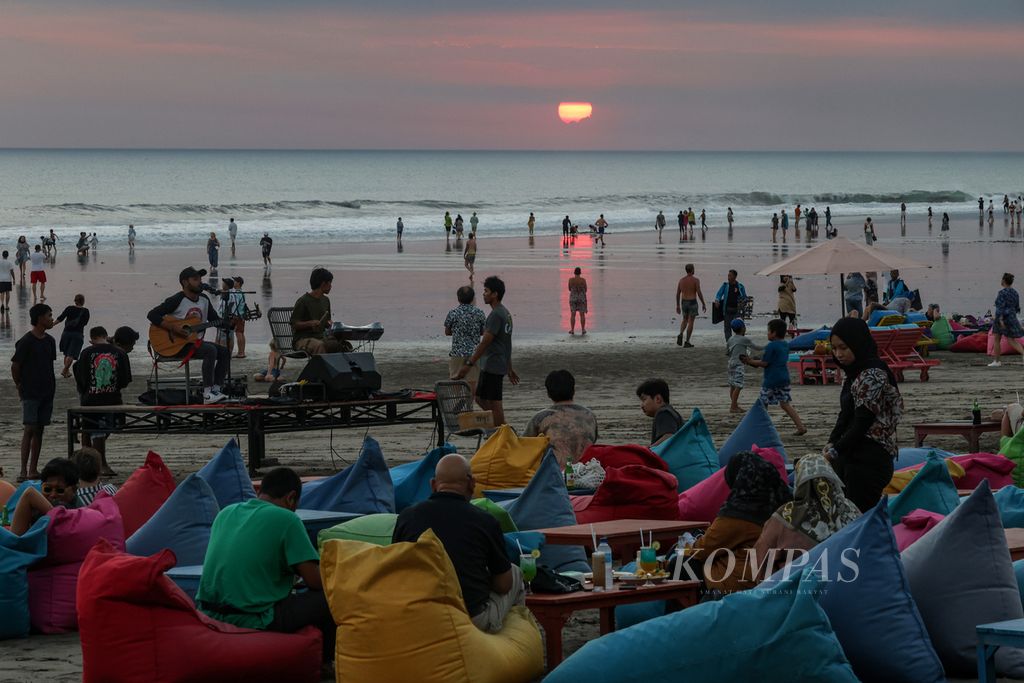 Wisatawan menikmati pemandangan matahari tenggelam di Pantai Seminyak, Kabupaten Badung, Bali, Jumat (10/5/2024). Pulau Bali memiliki sejumlah pantai eksotis yang memanjakan wisatawan, terutama bagi mereka yang ingin menikmati suasana sore hingga senja.  
