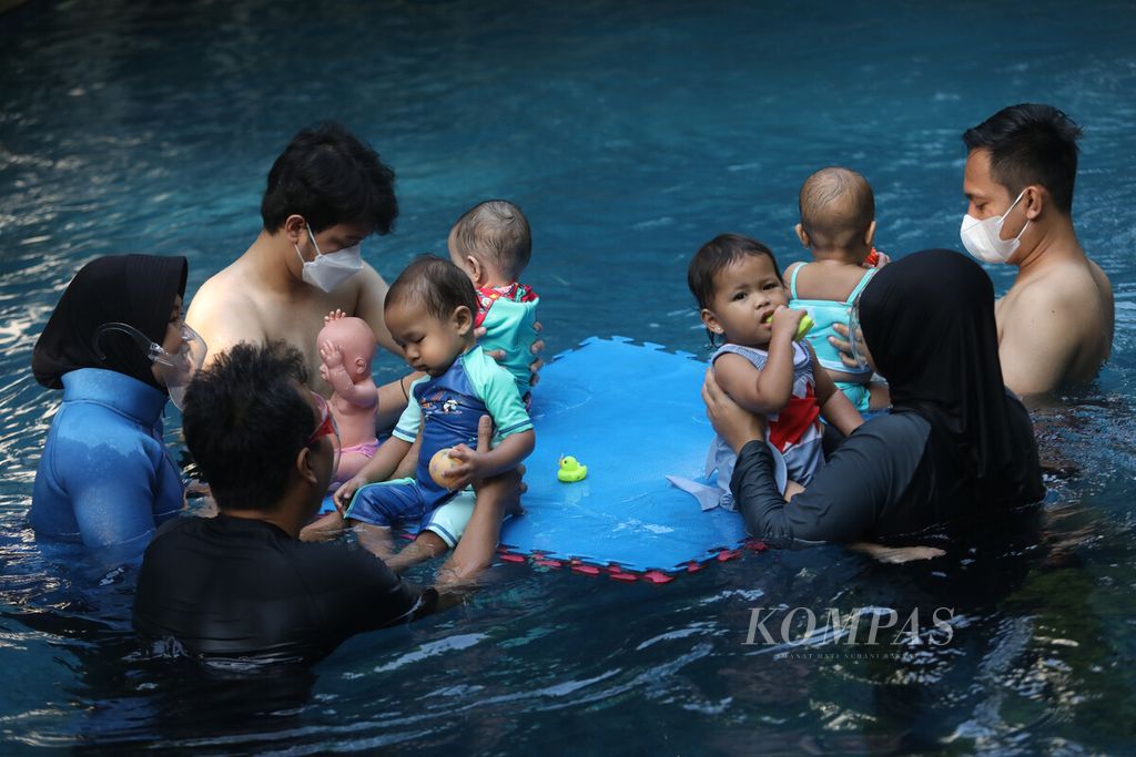 Sejumlah orangtua mendampingi bayi mereka berlatih renang dalam pelatihan khusus di sebuah kolam yang dikelola oleh Splish Splash Indonesia di kawasan Cempaka Putih, Jakarta, Sabtu (30/7/2022). 