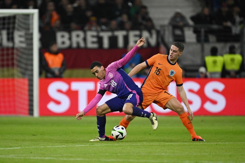 Pemain timnas Jerman Jamal Musiala (kiri) dan pemain timnas Belanda Joey Veerman berebut bola pada laga persahabatan melawan Belanda di Deutsche Bank Park, Frankfurt, Jerman, Selasa (24/3/2024). Jerman menang 2-1 pada laga itu.