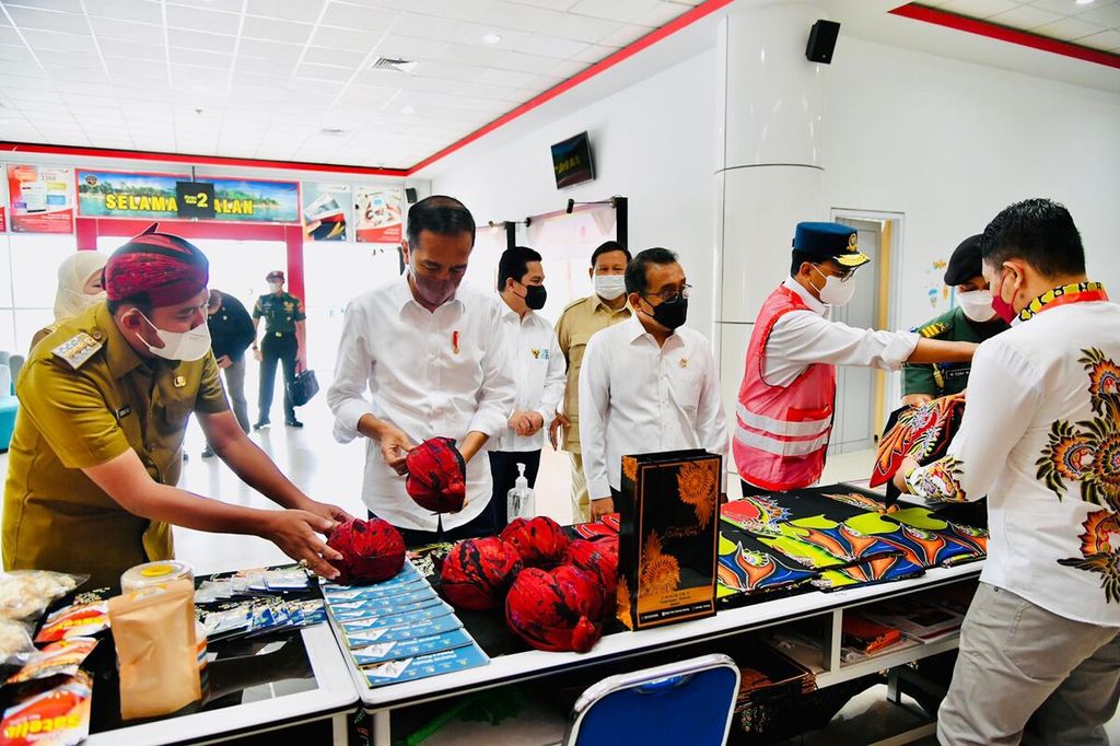 Presiden Joko Widodo membeli odheng, ikat kepala khas Madura, serta dua lembar kain batik di gerai UMKM di ruang tunggu Bandar Udara Trunojoyo, Sumenep, Madura, Jawa Timur. Bandara Trunojoyo diresmikan pada Rabu (20/4/2022).
