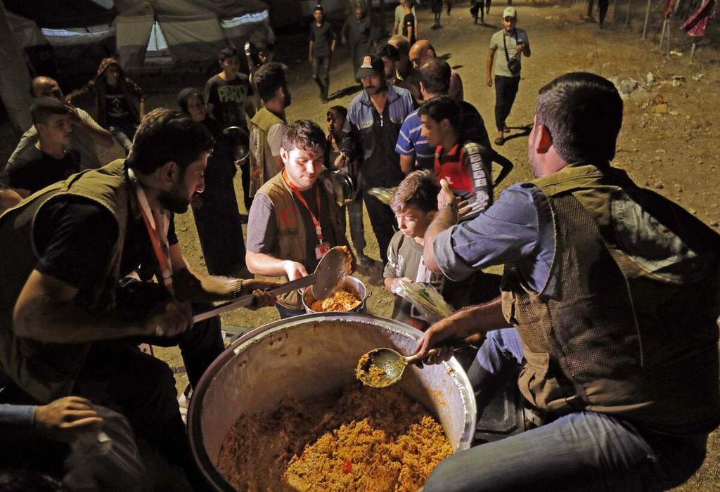 Relawan membagikan makanan kepada pengungsi Suriah di Kamp Bardarash, dekat kota Dohuk, wilayah otonomi Kurdi, Irak, 20 Oktober 2019.