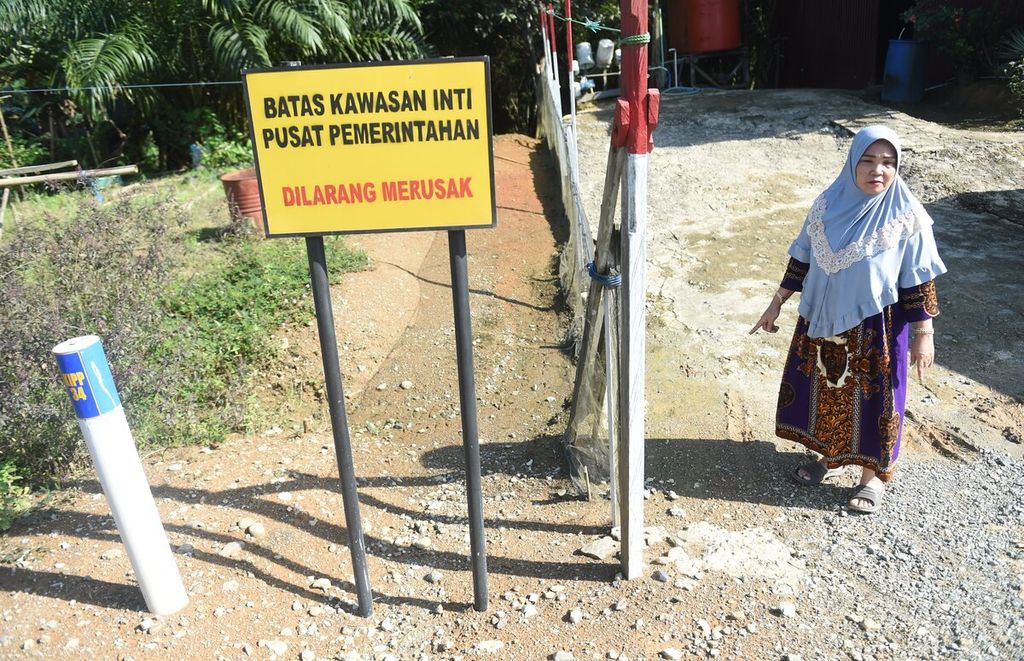Raniah (57) berada di samping papan peringatan batas inti pusat pemerintahan di sebelah halaman rumahnya di Desa Bumi Harapan, Kecamatan Sepaku, Kabupaten Penajam Paser Utara, Kalimantan Timur, Selasa (26/7/2022). 