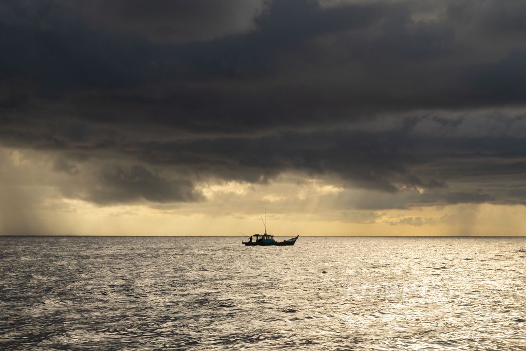 Sebuah perahu kayu nelayan bergerak menghindari hujan saat menangkap ikan tongkol di perairan yang berjarak sekitar 45 kilometer di sebelah timur Pulau Natuna Besar, Kepulauan Riau, Sabtu (26/3/2022).