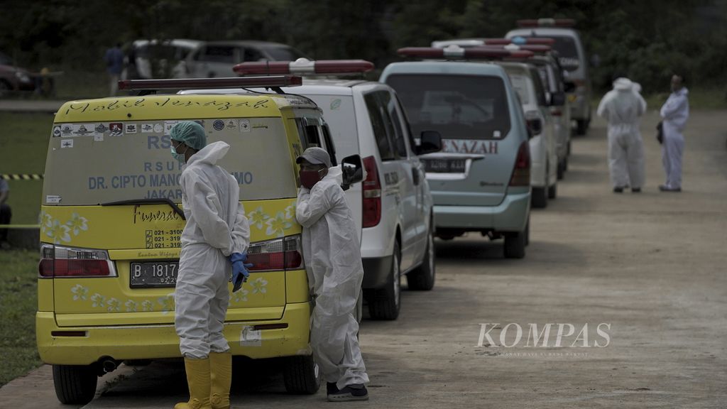 Sopir ambulans antre menurunkan jenazah dalam pemakaman dengan protokol Covid-19 di Tempat Pemakaman Umum  Bambu Apus, Cipayung, Jakarta Timur, Selasa (26/1/2021).
