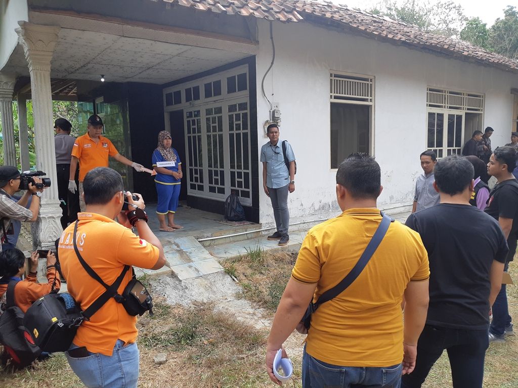 Saminah, tersangka kasus pembunuhan, melakukan rekonstruksi saat mencegah salah satu tetangganya masuk ke rumahnya karena curiga terdengar jeritan dari rumah tersangka, Rabu (28/8/2019), di Desa Pasinggangan, Banyumas, Jawa Tengah.