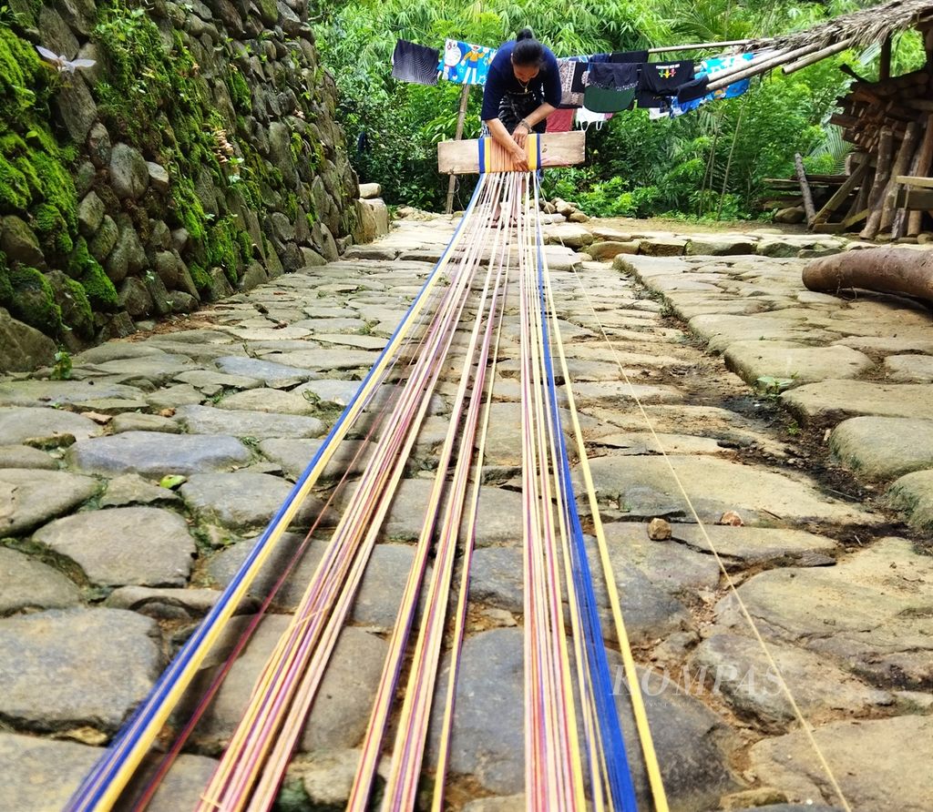 Warga Kampung Cicakal, Baduy Luar, merangkai dan menyusun untaian benang yang akan dipasang pada <i>pakara</i>, alat menenun, Kamis (27/10/2022).