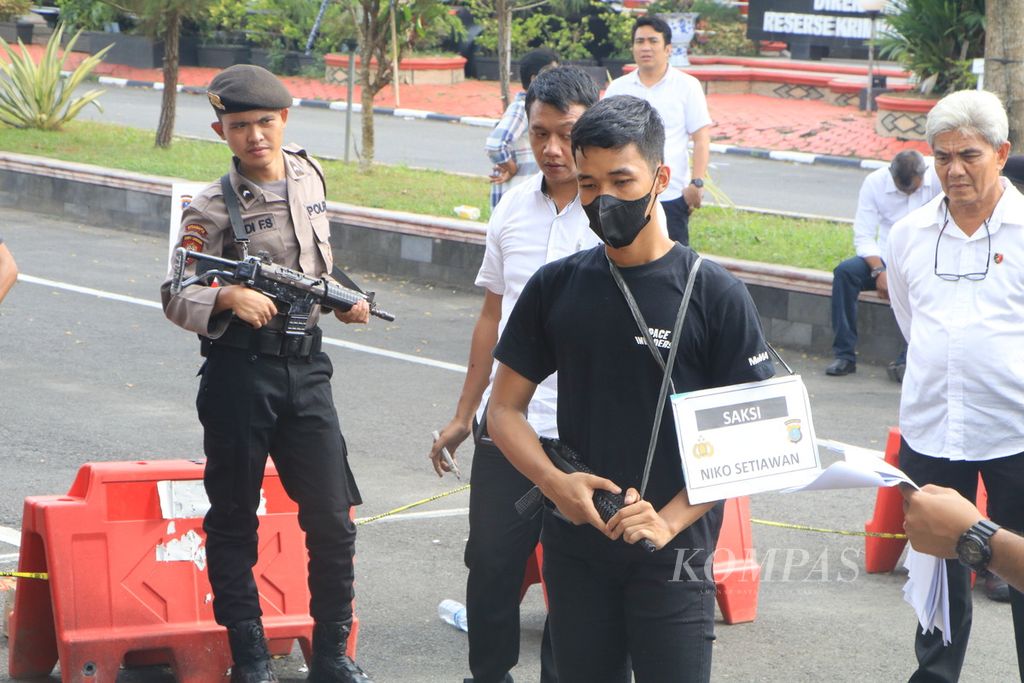 Saksi Nico Setiawan menenteng senjata laras panjang dalam reka ulang kasus penganiayaan oleh Aditya Hasibuan terhadap korban Ken Admiral di Kepolisian Daerah Sumatera Utara, Senin (8/5/2023).  Kasus ini viral di media sosial sehingga mendapat perhatian dari pihak kepolisian.