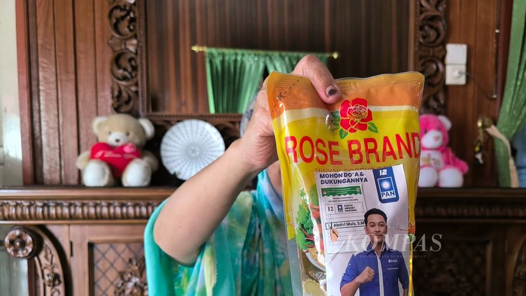 Warga menunjukkan minyak goreng yang diperoleh dari tim sukses salah satu calon anggota DPRD Kota Samarinda di Kecamatan Sungai Kunjang, Kota Samarinda, Kalimantan Timur, Senin (18/12/2023).