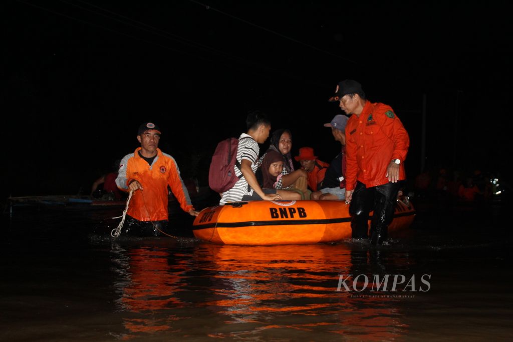 Officials assist residents who wish to cross in Kalahien Village, South Hamlet District, South Barito Regency, Central Kalimantan, on Wednesday (24/1/2024). The Trans-Kalimantan road was impassable for five days due to floods with a depth of at least 1.5 meters.