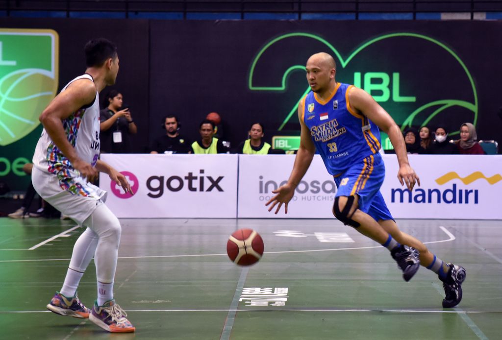 Small forward Satria Muda Pertamina Jakarta Arki Dikania Wisnu (biru) mencoba menerobos pengawalan Bali United Basketball Club dalam laga seri keenam Liga Bola Basket Indonesia atau IBL 2023 di GOR Amongraga, Yogyakarta, Sabtu (27/5/2023). Satria Muda menang 80-62. Mereka pun kembali ke puncak klasemen dengan 39 poin dari 20 laga. 