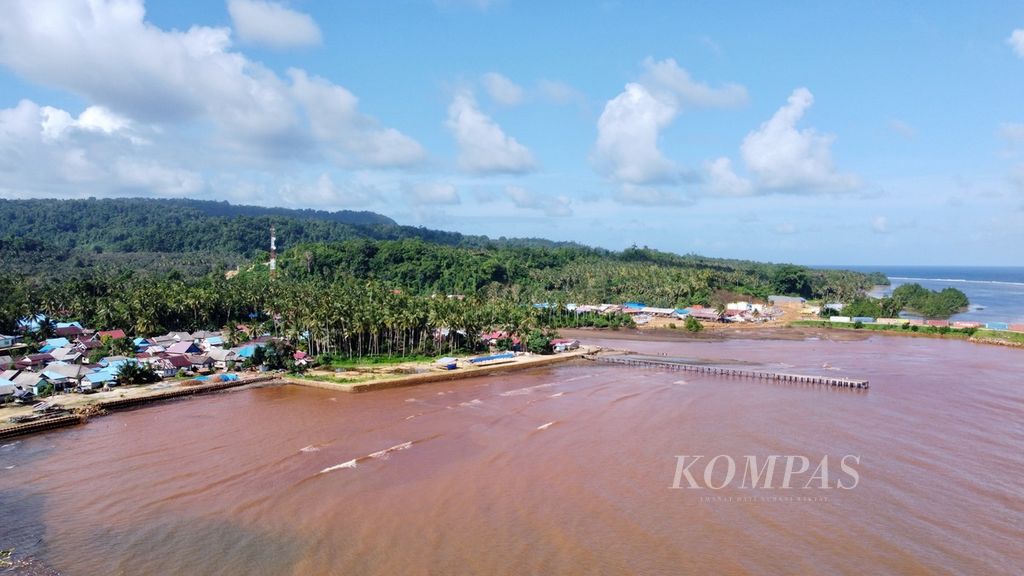 Jejeran kelapa, pemukiman, dan laut yang memerah di pesisir Desa Sukarela Jaya, Wawonii Tenggara, Konawe Kepulauan, Kamis (1/6/2023). Warga berupaya berdaya dengan perkebunan di tengah impitan pertambangan yang beroperasi di wilayah ini.
