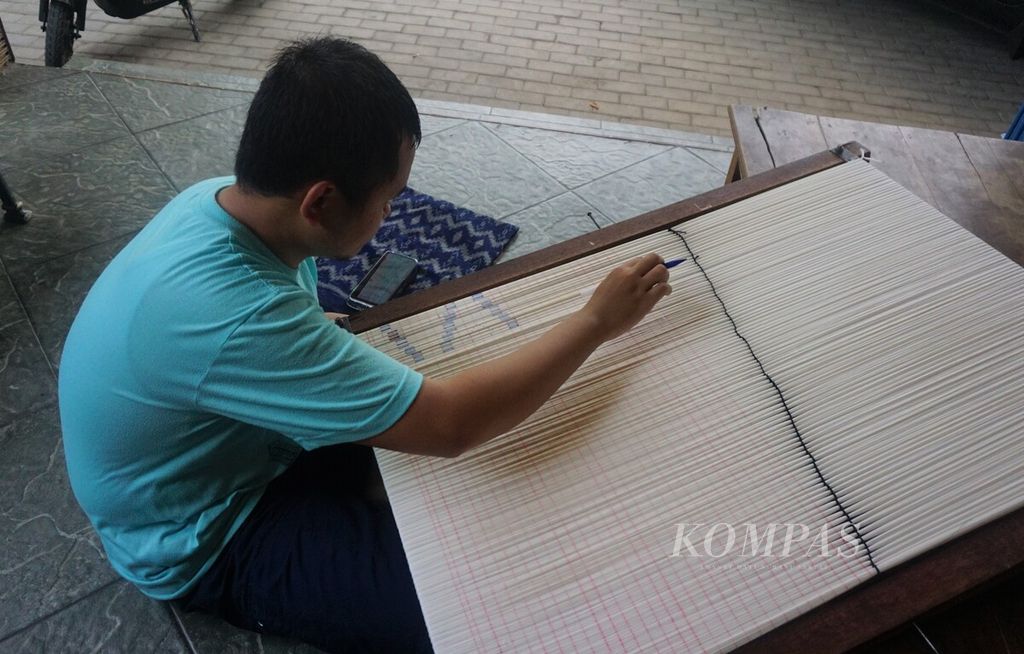 Deni, penyandang autisme, Senin (16/10/2023) di rumah artisan tenun Siti Roqayah, di Bandarkidul Kota Kediri, Jawa Timur, menggambar motif sebagai bagian dari proses pembuatan kain tenun ikat Kediri. 