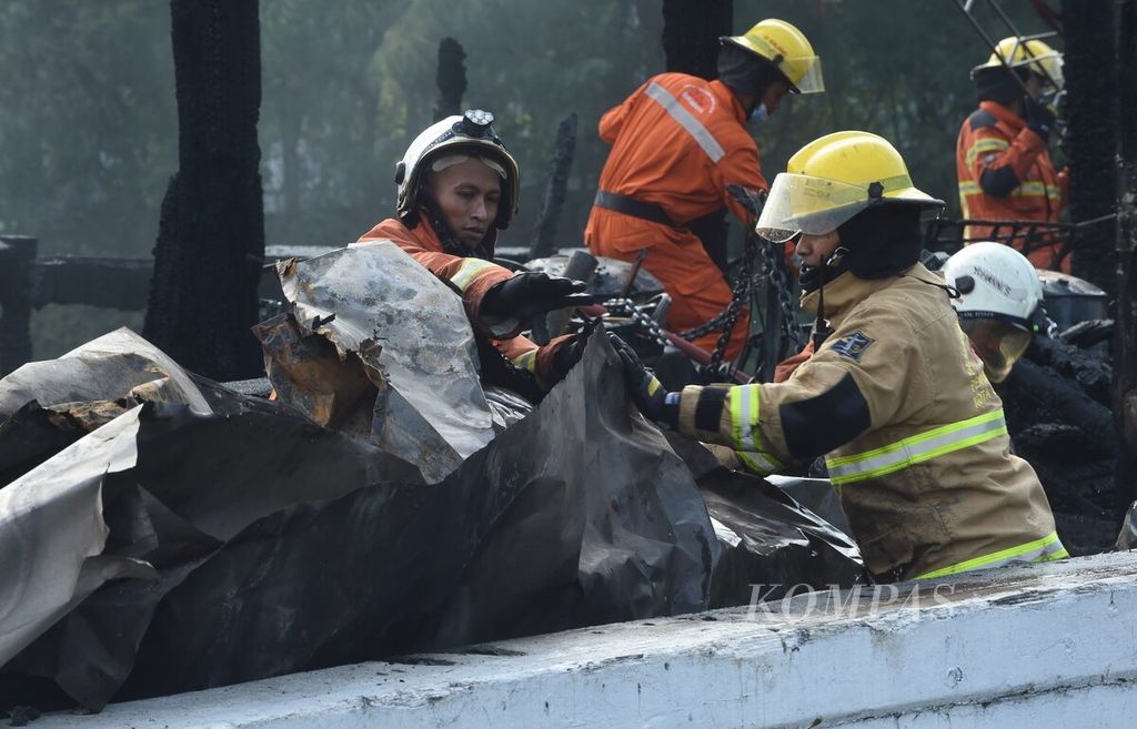 Petugas pemadam kebakaran saat  melakukan pembasahan ke kapal layar motor yang terbakar di Pelabuhan Kalimas, Kota Surabaya, Jawa Timur, Minggu (17/7/2022). 