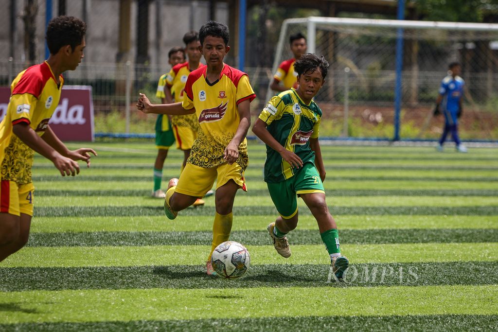 Pemain Salfas Soccer, Rido (kiri), berebut bola dengan pemain Siaga Pratama, Kurniansyah Rizki, dalam laga pekan kesembilan Liga Kompas Kacang Garuda U-14 di Dewantara Sport Center, Tangerang Selatan, Banten, Minggu (21/1/2024). 
