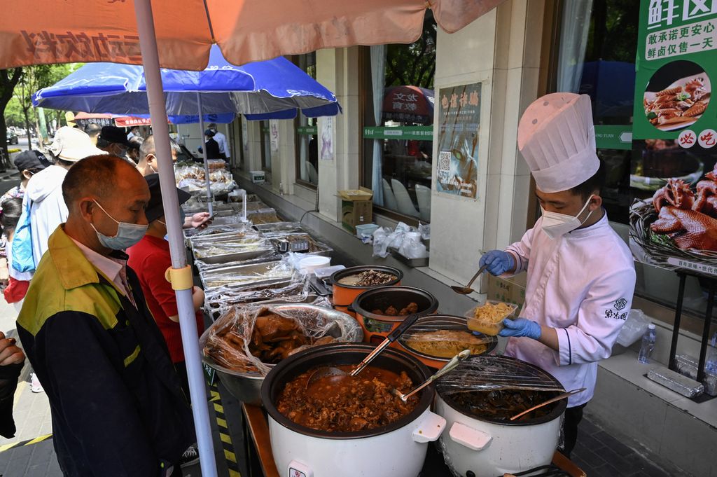 Pelayan menyiapkan makanan yang hendak dibawa pulang oleh konsumen di luar sebuah restoran, di Beijing, China, Kamis (5/5/2022). Pemerintah China melarang warga untuk makan di restoran guna mencegah penularan Covid-19. 