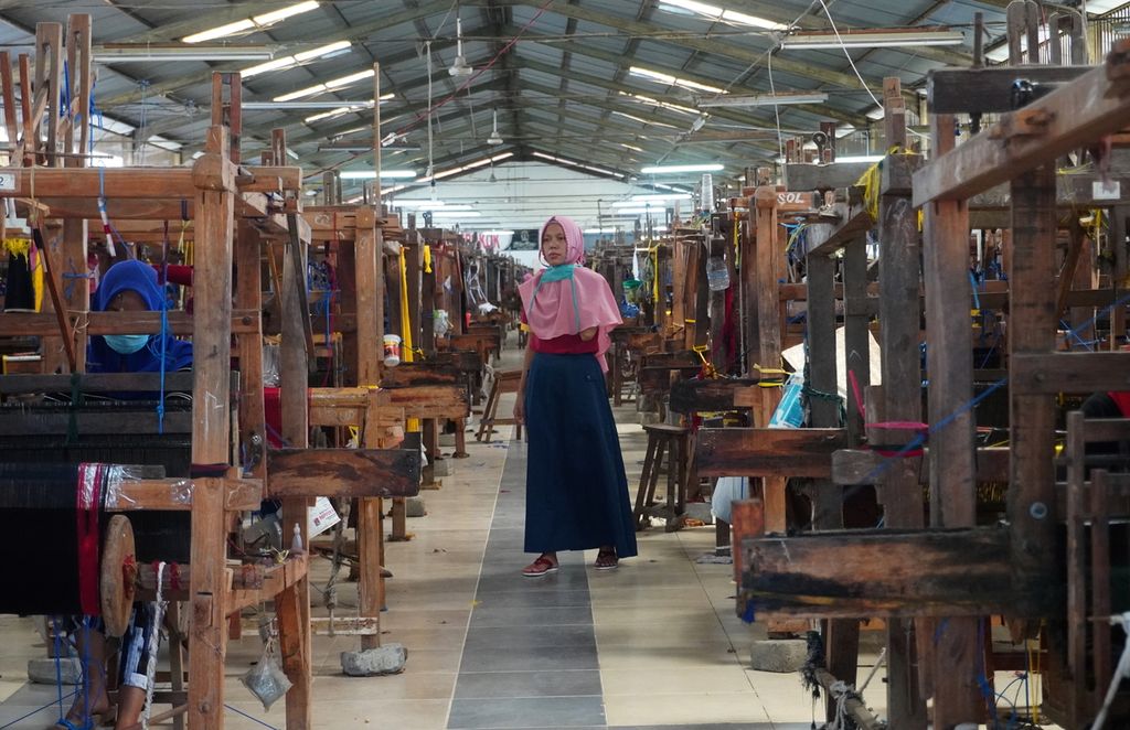 Pekerja berjalan di sebuah pabrik pembuatan sarung menggunakan alat tenun bukan mesin di Desa Wangandawa, Kecamatan Talang, Kabupaten Tegal, Jateng, Sabtu (24/4/2021). Sejak pertengahan tahun lalu, pekerja urban yang terdampak pandemi pulang ke Tegal dan bekerja di pabrik tersebut sehingga jumlah pekerja di pabrik itu bertambah dari 960 orang menjadi 1.600 orang. Adapun kapasitas produksi sarung tenun berorientasi ekspor itu bertambah dari 300 lembar per hari menjadi 1.000 lembar per hari.