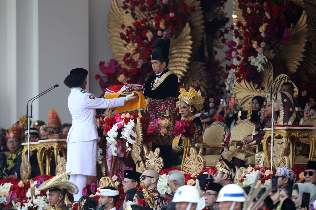 Presiden Joko Widodo menyerahkan Sang Saka Merah Putih kepada Lily Wenda, anggota Pasukan Pengibar Bendera Pusaka (Paskibraka) yang bertugas membawa baki, dalam Upacara Peringatan Detik-detik Proklamasi Kemerdekaan Ke-78 Republik Indonesia di Istana Merdeka, Jakarta, Kamis (17/8/2023). 