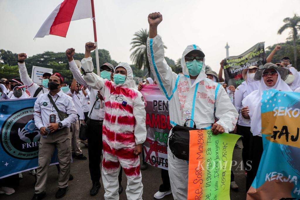 Two participants in the protest used protective gear during the rally in the Arjuna Wiwaha Horse Statue area, Jakarta, on Monday (7/8/2023). Hundreds of non-permanent healthcare workers who are members of the Honorary Communication Forum for Nakes and Nonnakes held a demonstration demanding the government to issue specific regulations to appoint non-permanent workers as civil servants.