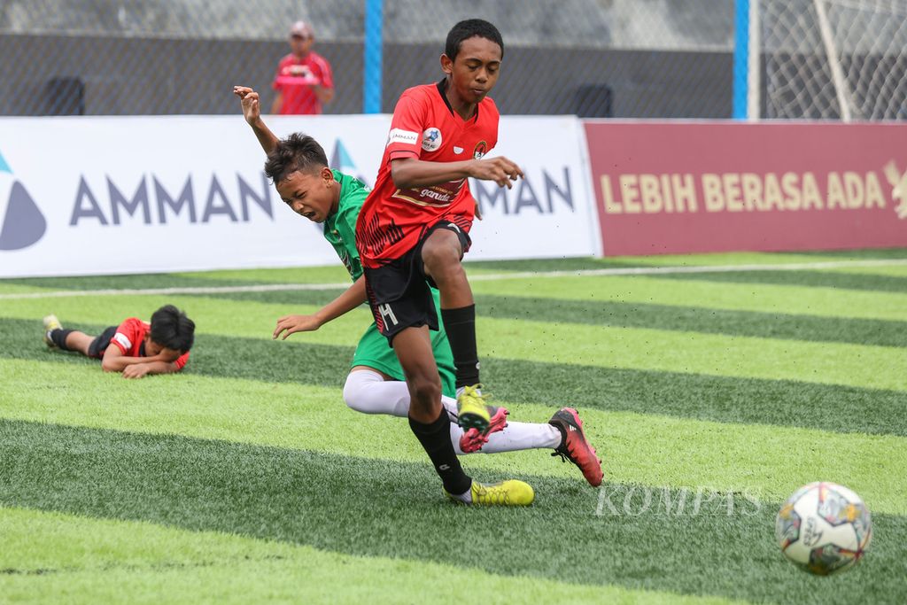 Pemain Putra Agung Christian Brilly Aipassa (kanan) beradu dengan pemain Buperta Cibubur Ryo Julian Agusto Salim pada pertandingan Liga Kompas Kacang Garuda U-14 di Dewantara Sport Center, Tangerang Selatan, Banten.