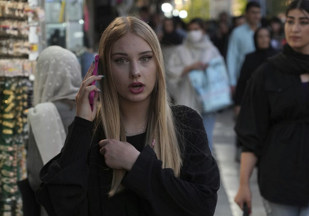 Seorang perempuan tanpa mengenakan kerudung berbicara melalui telepon seluler saat berjalan di kawasan bisnis Tajrish, Teheran, Iran, 29 April 2023. 