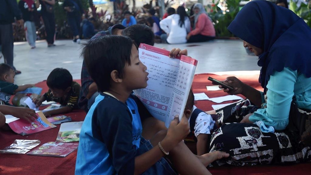 Anak membaca buku yang dipinjam di Perpustakaan Keliling Kota Surabaya di Taman Bungkul, Surabaya, Jawa Timur, Minggu (10/3/2019). Selain menghadirkan perpustakaan keliling di Taman Kota, untuk meningkatkan minat baca warga, pemerintah kota membangun taman bacaan di setiap kelurahan di Kota Surabaya.