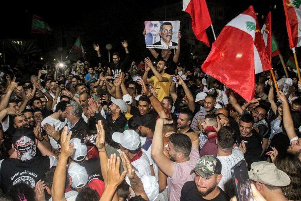 Massa pendukung calon anggota parlemen Lebanon, Osama Saad, dari Organisasi Nasserist Populer, mengangkat potret dan bendera partainya dan Partai Komunis Lebanon saat mereka bersorak-sorai atas berakhirnya pemungutan suara pemilu parlemen di kota Sidon, Lebanon selatan, 15 Mei 2022. 