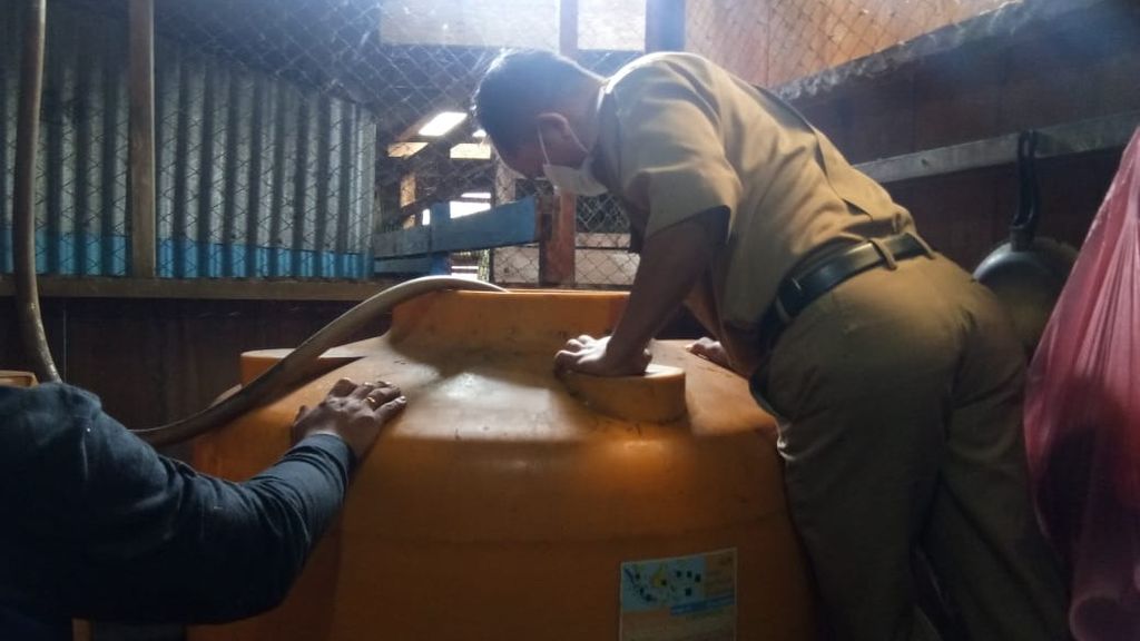 Petugas Dinas Kesehatan Kabupaten Asmat menaburkan bubuk abate ke tempat penampungan air di rumah warga di Distrik Agats, Kabupaten Asmat, Papua, Senin (4/7/2022).