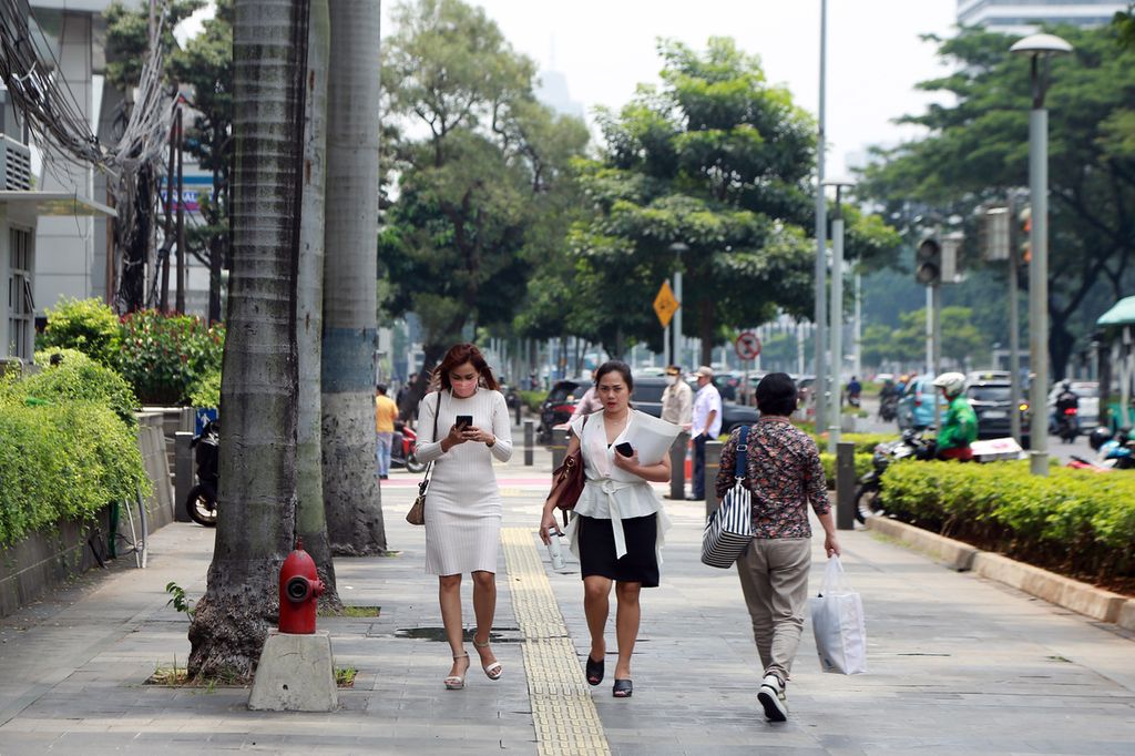 Karyawan melintasi jalur pedestrian saat istirahat jam makan siang di Jalan Jenderal Sudirman, Jakarta Selatan, Rabu (02/11/2022). Jumlah karyawan formal di Jakarta dalam dua tahun terakhir terus mengalami kenaikan. Survei Badan Pusat Statistik mencatat di tahun 2020 jumlah karyawan formal 2,8 juta jiwa, naik sekitar 100.000 jiwa pada 2021.