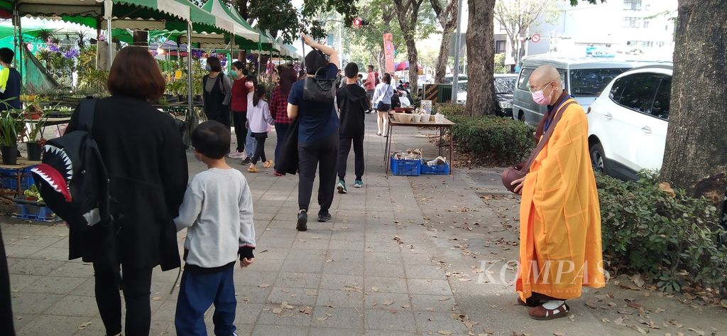 Seorang biksuni menunggu pejalan kaki memberi sedekah di salah satu trotoar di Kaohsiung, Taiwan, Minggu (22/2/2023) yang merupakan Tahun Baru Imlek 2023.