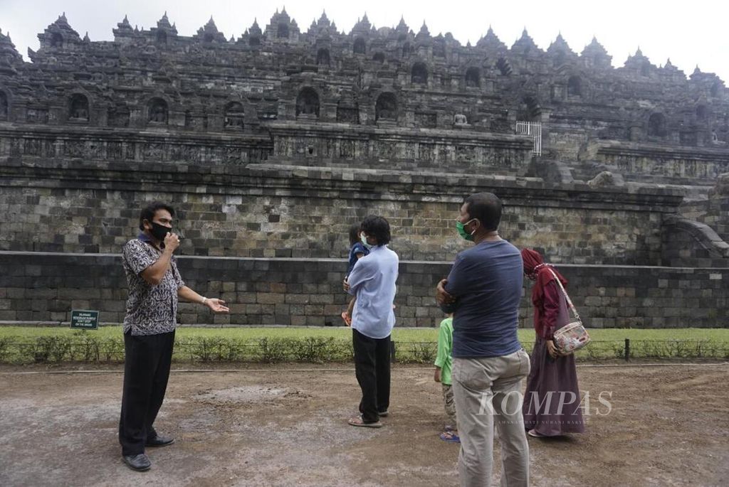Seorang pemandu wisata (kiri) memberikan penjelasan kepada pengunjung Taman Wisata Candi Borobudur dalam acara simulasi pembukaan zona I Candi Borobudur, Jumat {26/6/2020).
