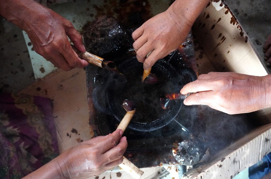 Perajin mencelupkan canting ke dalam wajan berisi malam untuk membatik di Desa Kaliwlingi, Kabupaten Brebes, Jawa Tengah, Selasa (13/4/2021).