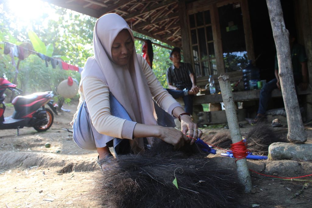 Seorang warga Desa Jayagiri, Kecamatan Sindangbarang, Kabupaten Cianjur, Jawa Barat, merajut ijuk menjadi sapu, Kamis (25/5/2023).