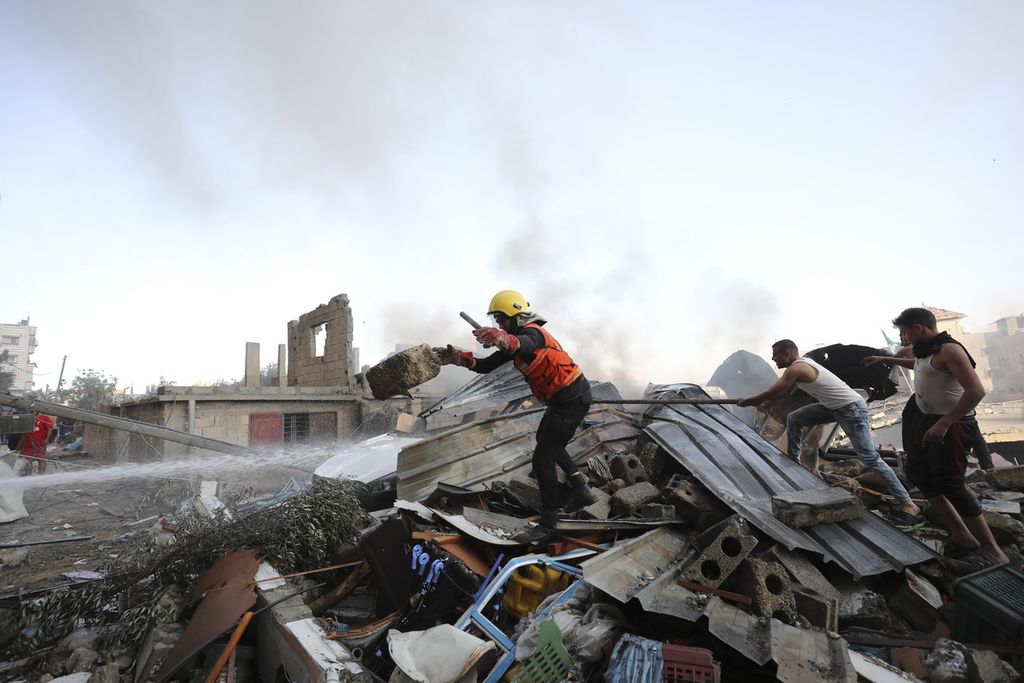 Regu penyelamat dibantu warga tengah mencari korban yang mungkin berada di retuntuhan bangunan setelah Israel melakukan serangan udara terhadap Kamp Pengungsi Nusseirat di kota Gaza, Rabu (18/10/2023).  