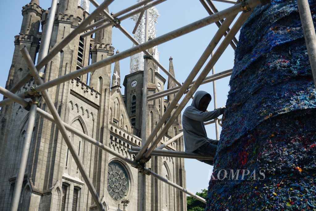 Seorang pekerja menyusun sebuah pohon natal dengan bahan dasar sampah plastik di halaman Gereja Katedral Santa Maria Diangkat ke Surga, Pasar Baru, Jakarta Pusat, Kamis (14/12/2023). 