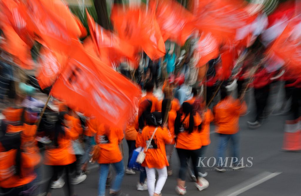 Peserta aksi membawa bendera serikat pekerja saat mereka berjalan bersama untuk merayakan Hari Buruh Internasional di depan Kantor DPRD Jawa Tengah, Kota Semarang, Senin (1/4/2023). 