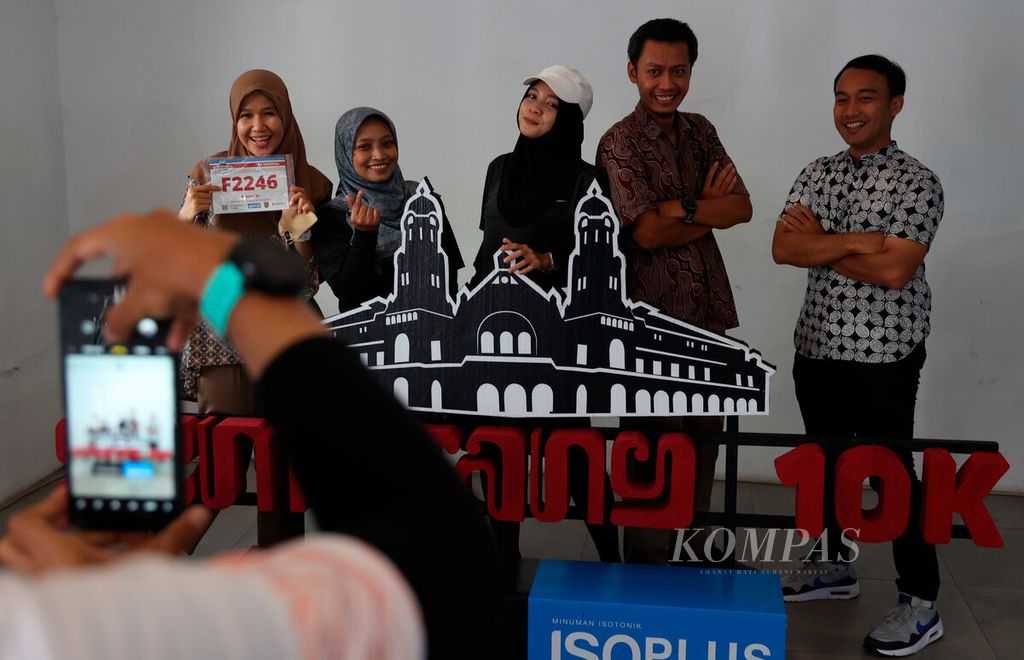 Peserta lari berfoto bersama dengan latar depan salah satu ikon Semarang 10K Powered by Isoplus di kawasan Kota Lama, Kota Semarang, Jawa Tengah, Jumat (16/12/2022).