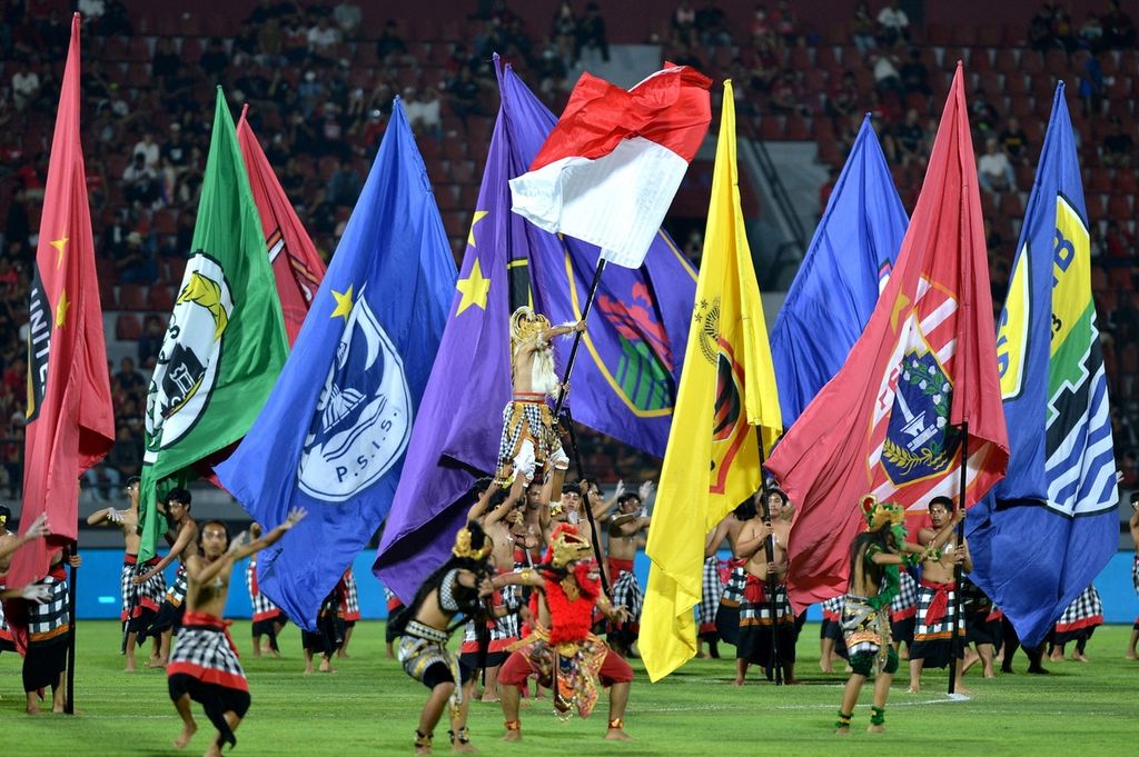 Sejumlah penari membawa bendera Merah Putih dan bendera klub peserta Liga 1 saat pembukaan kompetisi Liga 1 2022/2023 di Stadion Kapten I Wayan Dipta, Gianyar, Bali, Sabtu (23/7/2022). Kompetisi Liga 1 musim 2022/2023 resmi dimulai dengan diikuti oleh 18 klub sepak bola. 