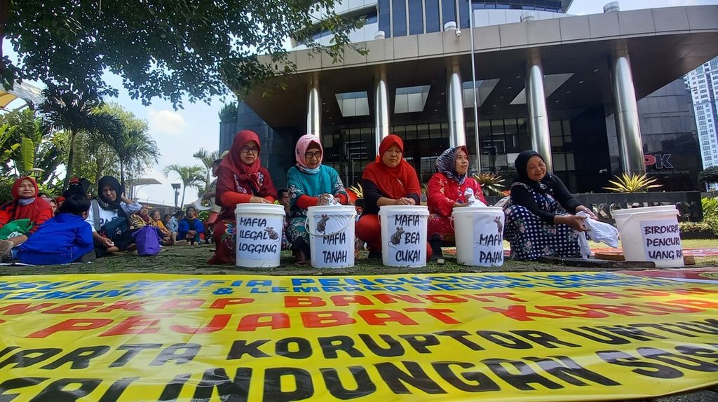 Lima perempuan anggota Serikat Perjuangan Rakyat Indonesia (SPRI) menampilkan aksi teatrikal mencuci baju di halaman Gedung Merah Putih Komisi Pemberantasan Korupsi di Jakarta, Kamis (16/3/2023). 