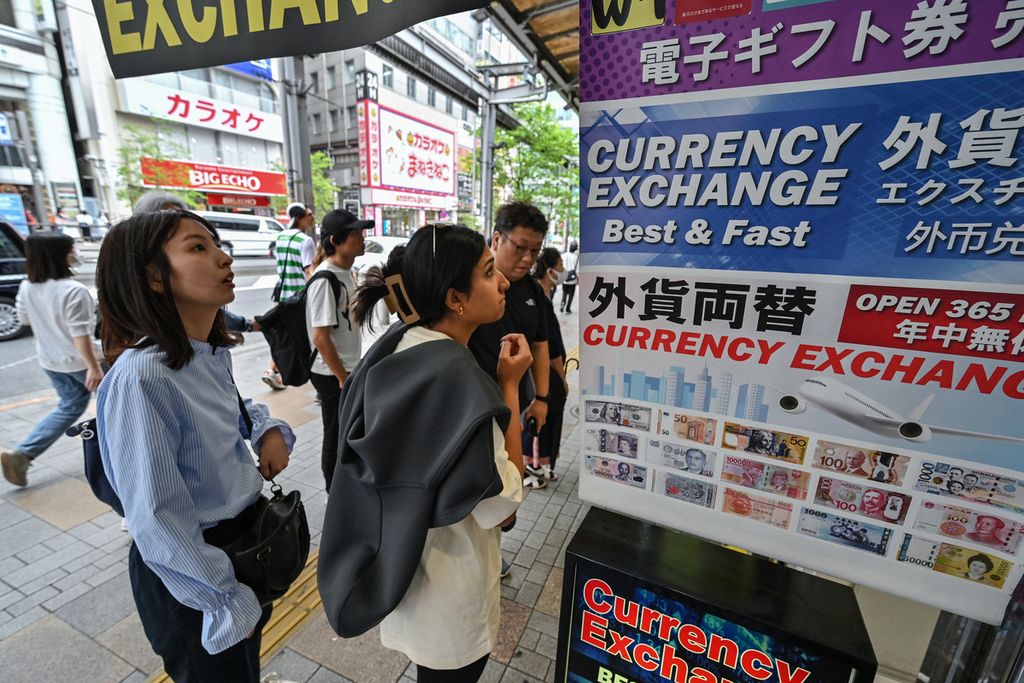 Warga berdiri di luar tempat penukaran uang sambil melihat kurs yen Jepang terhadap mata uang asing di sebuah jalan di pusat kota Tokyo, Jepang, 29 April 2024.