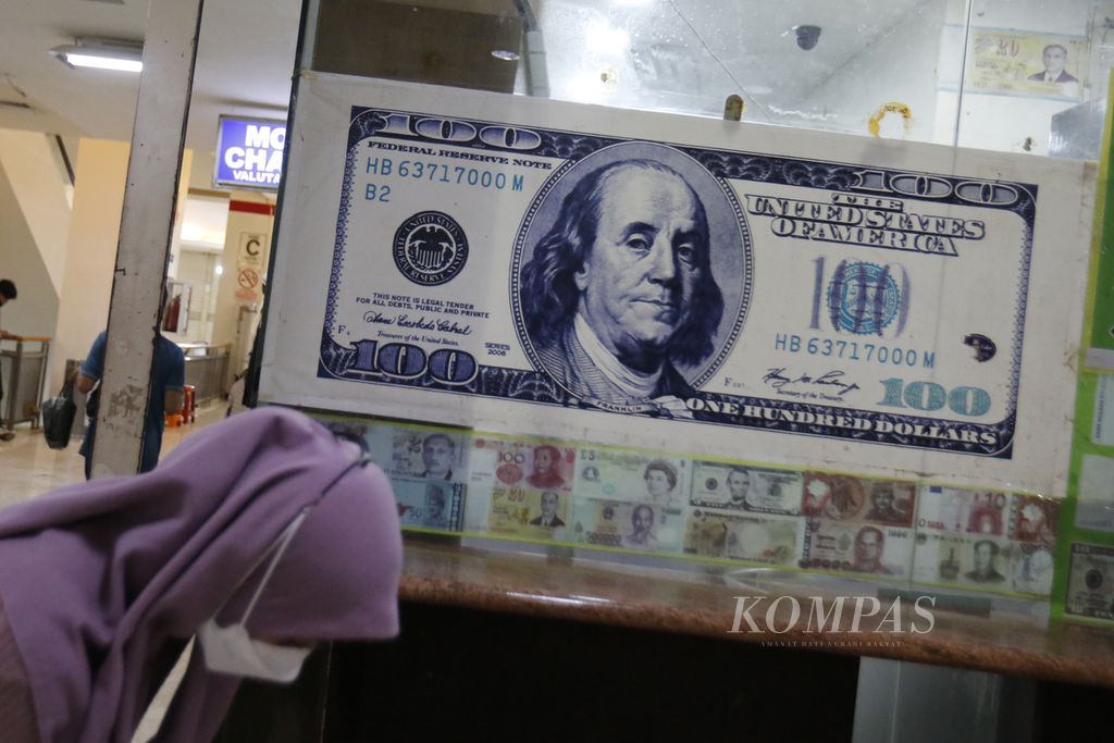 Warga melintas di depan gerai penukaran valuta asing di ITC Kuningan, Jakarta, Senin (7/8/2023). 