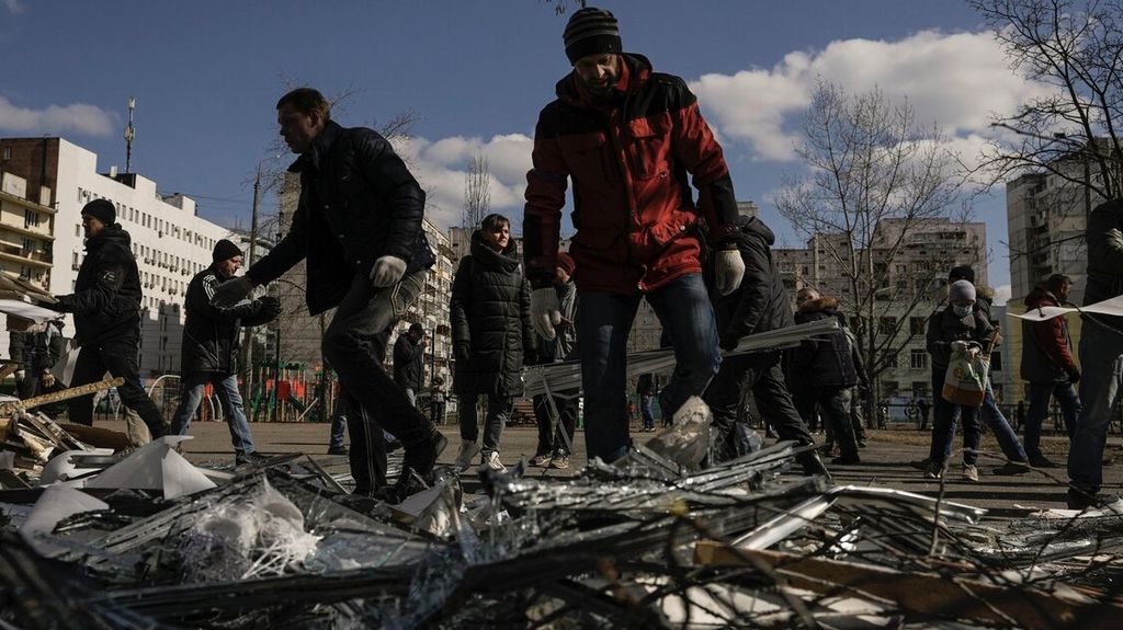 Orang-orang membersihkan puing-puing di luar pusat medis yang rusak setelah rudal Rusia yang ditembak jatuh oleh pertahanan udara Ukraina mendarat di salah satu blok apartemen di Kiev, Ukraina, Kamis (17/3/2022). 