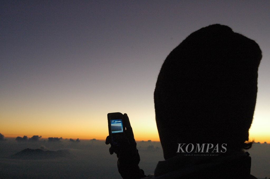 Foto seseorang mengabadikan pemandangan matahari terbit (<i>sunrise</i>) dari bibir Kawah Ijen, Banyuwangi, Jawa Timur, Selasa (29/6/2005) pukul 05.15 WIB, dengan telepon seluler yang masih sederhana.