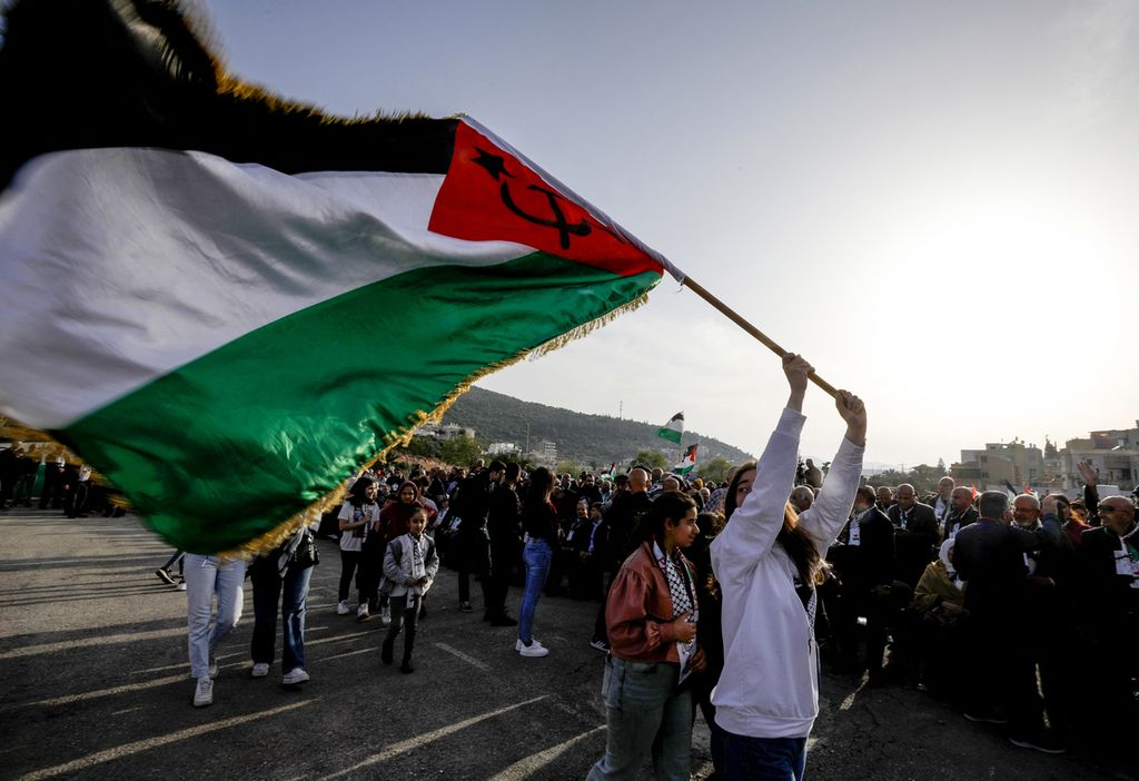Warga Arab-Israel memegang bendera Palestina saat peringatan Hari Bumi di kota Deir Hanna, wilayah Galilea, Israel, 30 Maret 2022. 