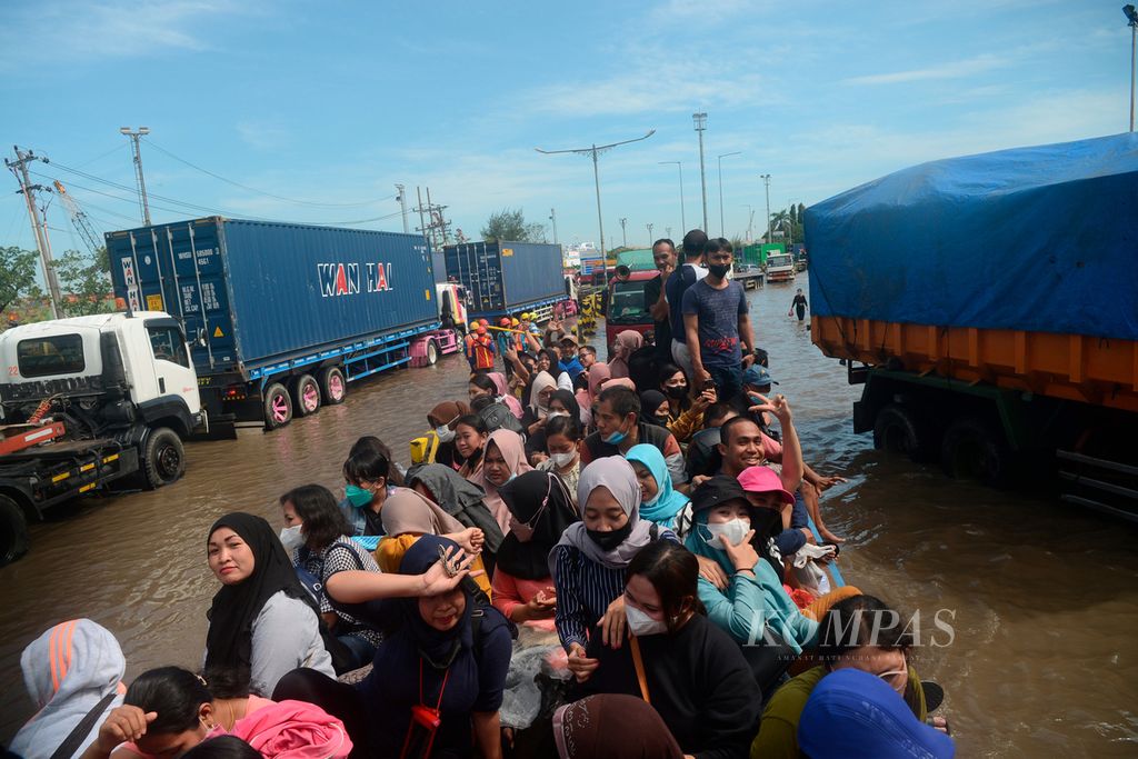Pekerja menumpang truk menuju tempat mereka bekerja di tengah antrean panjang kendaraan angkutan peti kemas di Pelabuhan Tanjung Emas, Kota Semarang, Jawa Tengah (27/5/2022). Banjir pasang air laut membuat aktivitas pelabuhan terganggu. 