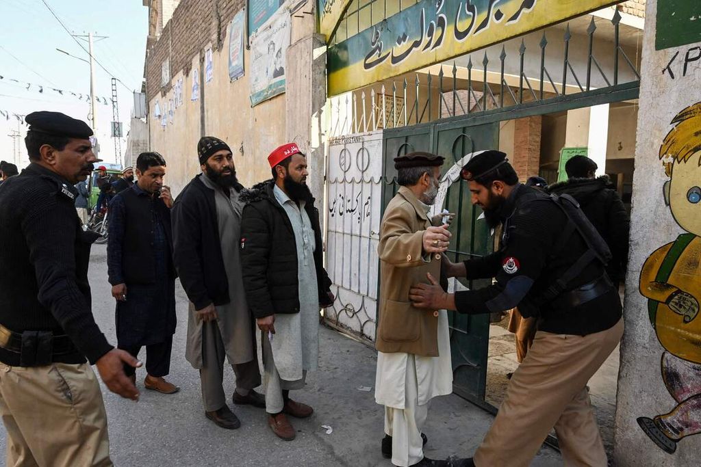 Seorang polisi (kanan) menggeledah warga pemilih yang akan memasuki sebuah tempat pemungutan suara dalam pemilu nasional di Peshawar, Pakistan, Kamis (8/2/2024). 