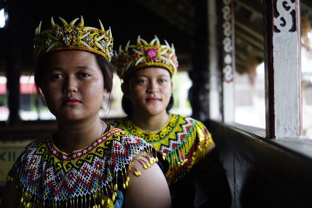 Gadis Dayak Kenyah sedang duduk di bagian depan rumah lamin atau rumah adat suku Dayak di Kelurahan Pampang, Kecamatan Samarinda, Kota Samarinda, Kalimantan Timur, Minggu (29/9/2019). Setiap akhir pekan, mereka tampil menari di rumah adat.