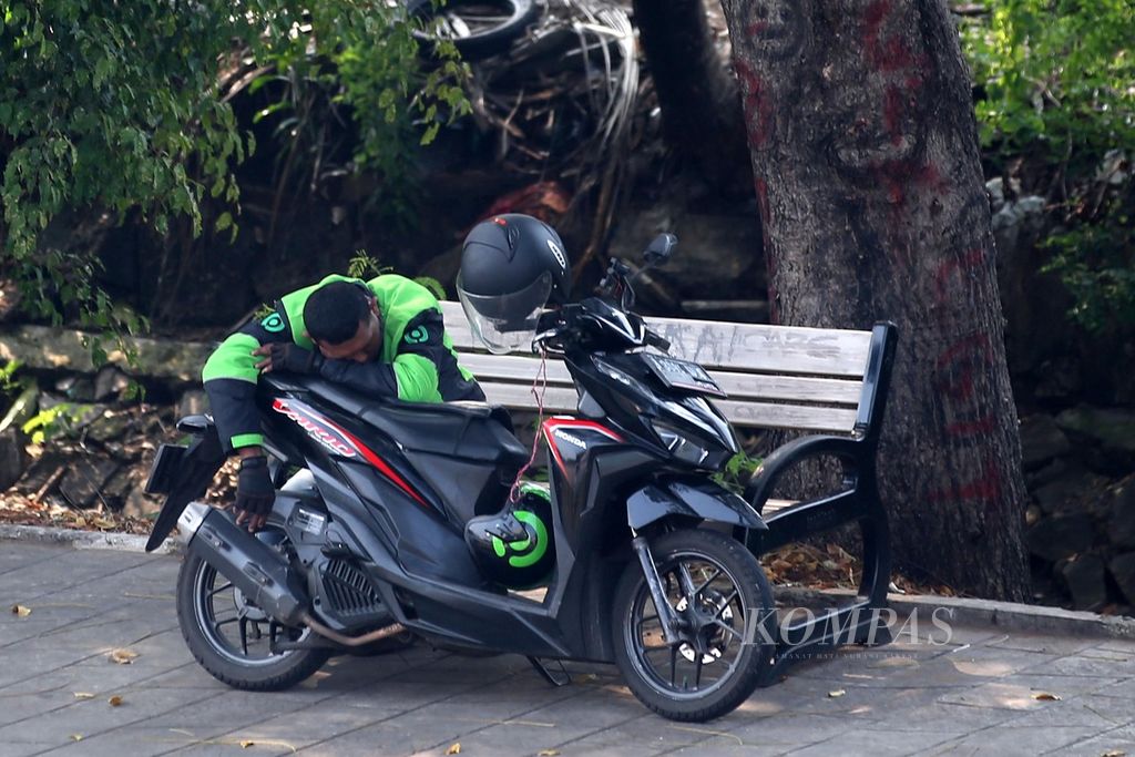 Pengemudi ojek daring terlelap saat menunggu orderan di Jalan Pemuda, Rawamangun, Jakarta Timur, Minggu (4/8/2024).