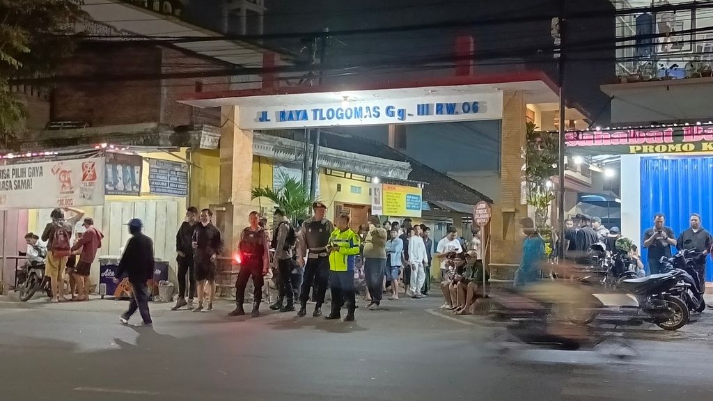 Warga bersama petugas keamanan berjaga di pintu masuk gang di Kelurahan Tlogomas, Kecamatan Lowokwaru, Kota Malang, Jawa Timur, Minggu (25/6/2023) malam.