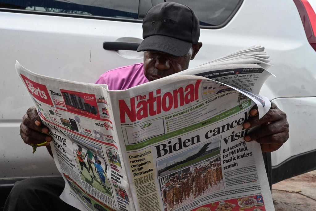 Seorang warga Papua Niugini membaca koran yang melaporkan antara lain pembatalan kunjungan Presiden Amerika Serikat, Joe Biden ke Papua Niugini ke Port Moresby, Kamis (18/5/2023).