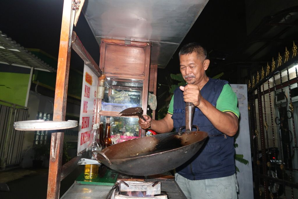 Penjual nasi goreng dok-dok keliling, Muhammad Ali, memasak di salah satu wilayah perumahan di Kemanggisan, Jakarta Barat, Rabu (12/10/2022) 